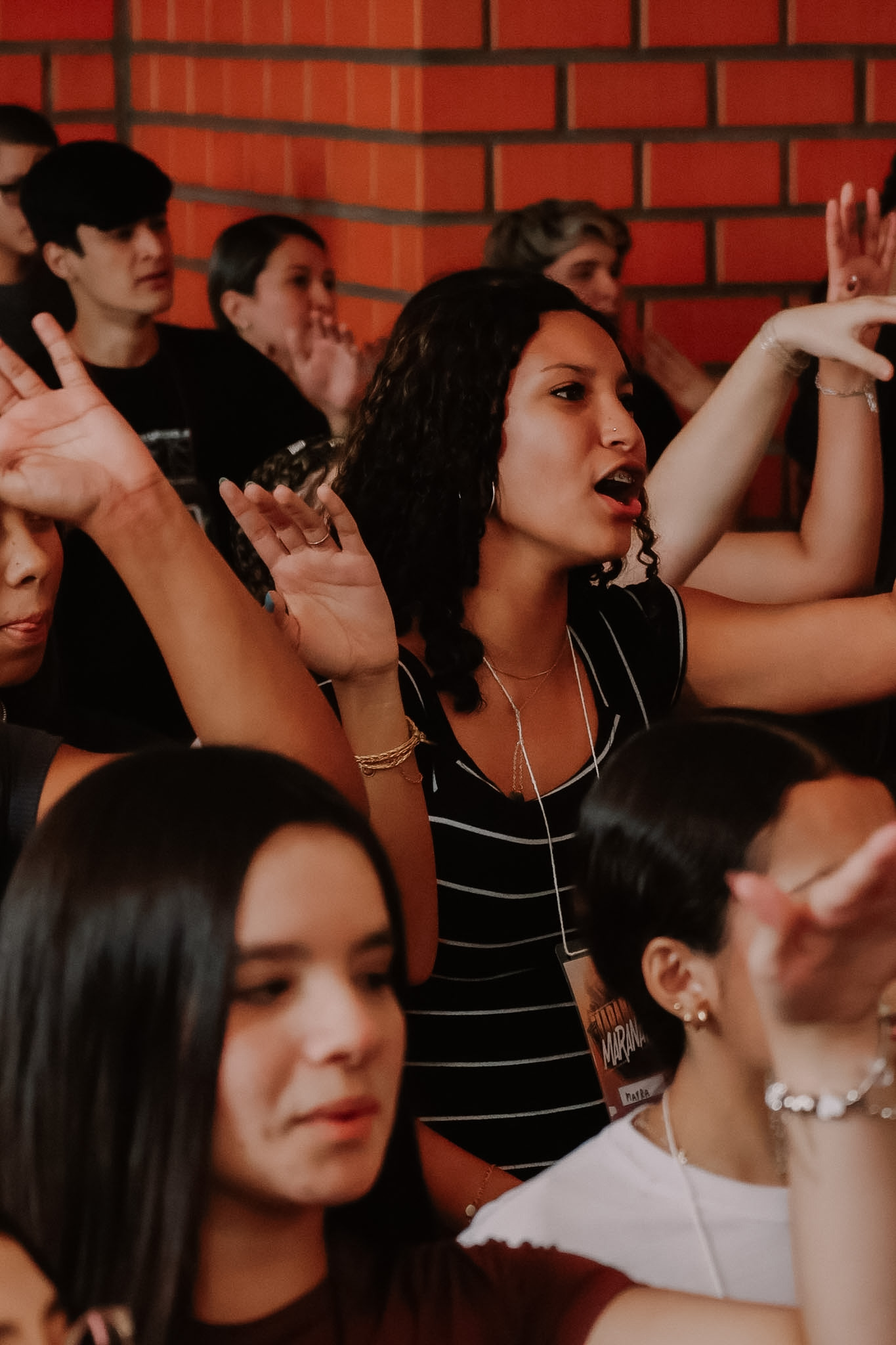 Jovem canta de mãos erguidas no meio da roda de louvor